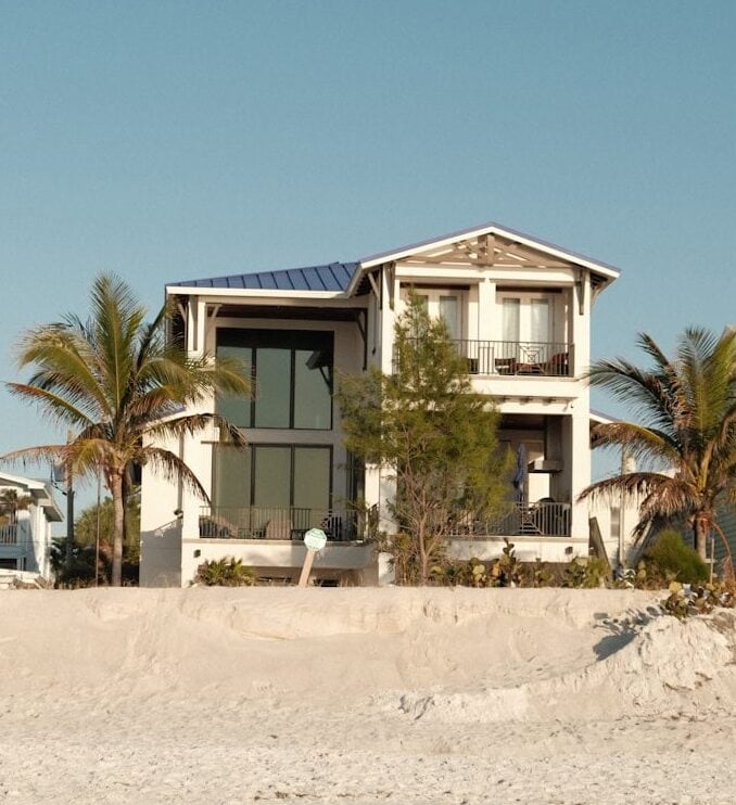 a house on the beach with a surfboard in front of it